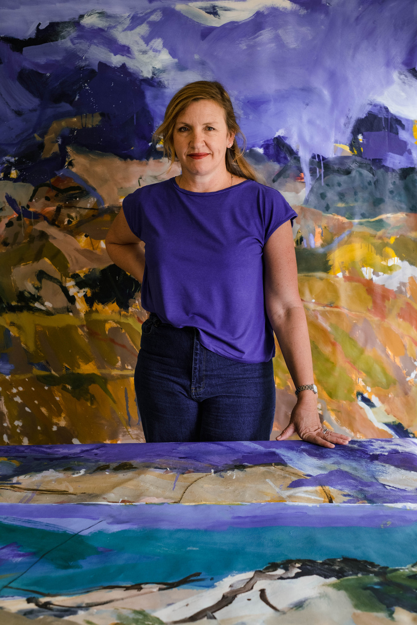 Artist in a purple shirt with her abstract painting